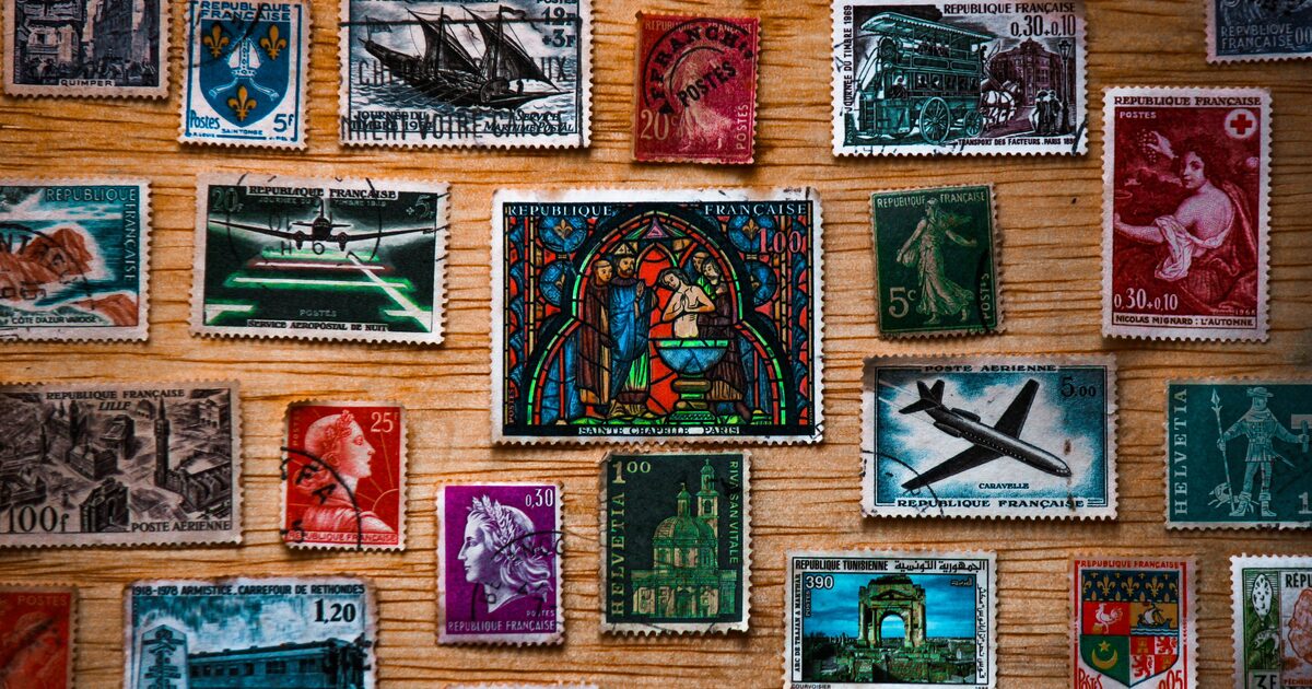 A grid of vintage world postage stamps arranged on a wooden surface